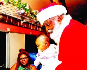 Mia Johnson  and her daughter, Addyson, were greeted by Santa on the first run of the Polar Express Wednesday night. Families and friends of employees of the holiday train were invited to ride during the practice run. Paying customers will board Friday for the first of 24 days of round trips to the North Pole and back. Last year more than 60,000 people rode the Batesville Polar Express during the holiday season. The fantasy excursion, which is inspired by the popular book and movie of the same name, is operated by Iowa Pacific Railroad, holder of the lease on the Grenada Railway line. Photo by Andy Young
